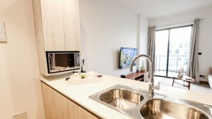 Eine moderne Küche mit Spüle aus Edelstahl, Holzschränken und einer Mikrowelle.