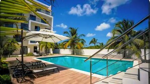 Ein modernes Hotel mit Schwimmbad, Palmen und blauem Himmel.