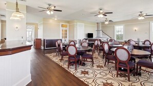 A spacious dining area with multiple tables and chairs, ceiling fans, and pendant lights. - Oak Cottage R301 (Lafitte)