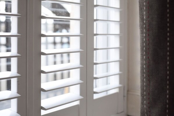 A window with white blinds partially open, allowing natural light to enter a room.