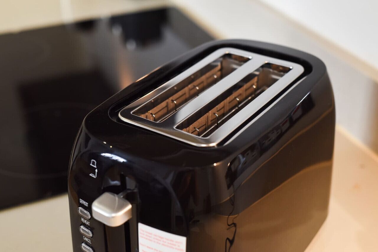 A black toaster with a transparent slot and a control panel with buttons labeled "DEPOSIT," "REHEAT," and "CANCEL."