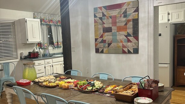 A dining area with a large wooden table, light blue chairs, a chandelier, and a colorful abstract painting on the wall. - Family Getaway! Book this home w/ 3 bedrooms/8 beds near Park City! (Heber City)