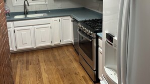 A kitchen with white cabinets, a stainless steel stove, a refrigerator, and a window with blinds. - Family Getaway! Book this home w/ 3 bedrooms/8 beds near Park City! (Heber City)