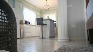 A kitchen with white cabinets, a black chair, and a chandelier. - Ocean Villa (Corinth)