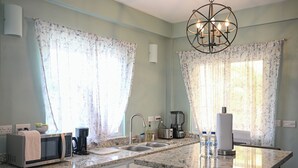 A kitchen with a microwave, toaster, sink, and a chandelier. - Ocean Villa (Corinth)