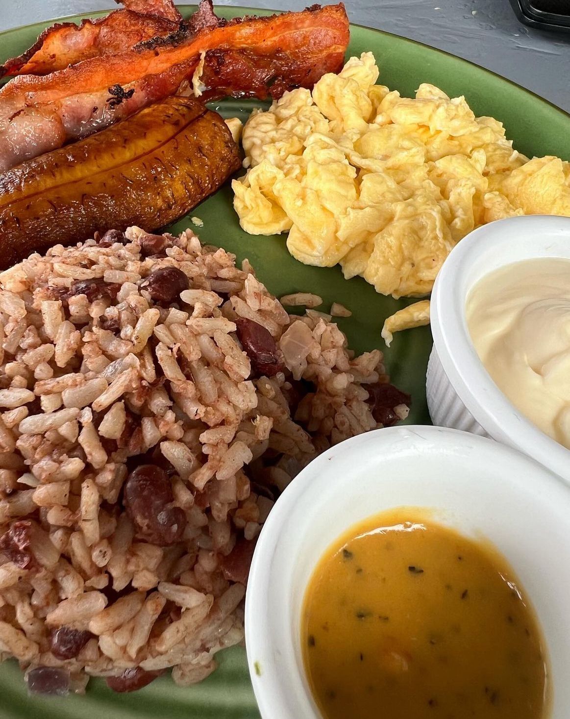 Une assiette de riz, d’œufs, de bananes plantains et une portion de sauce à part.