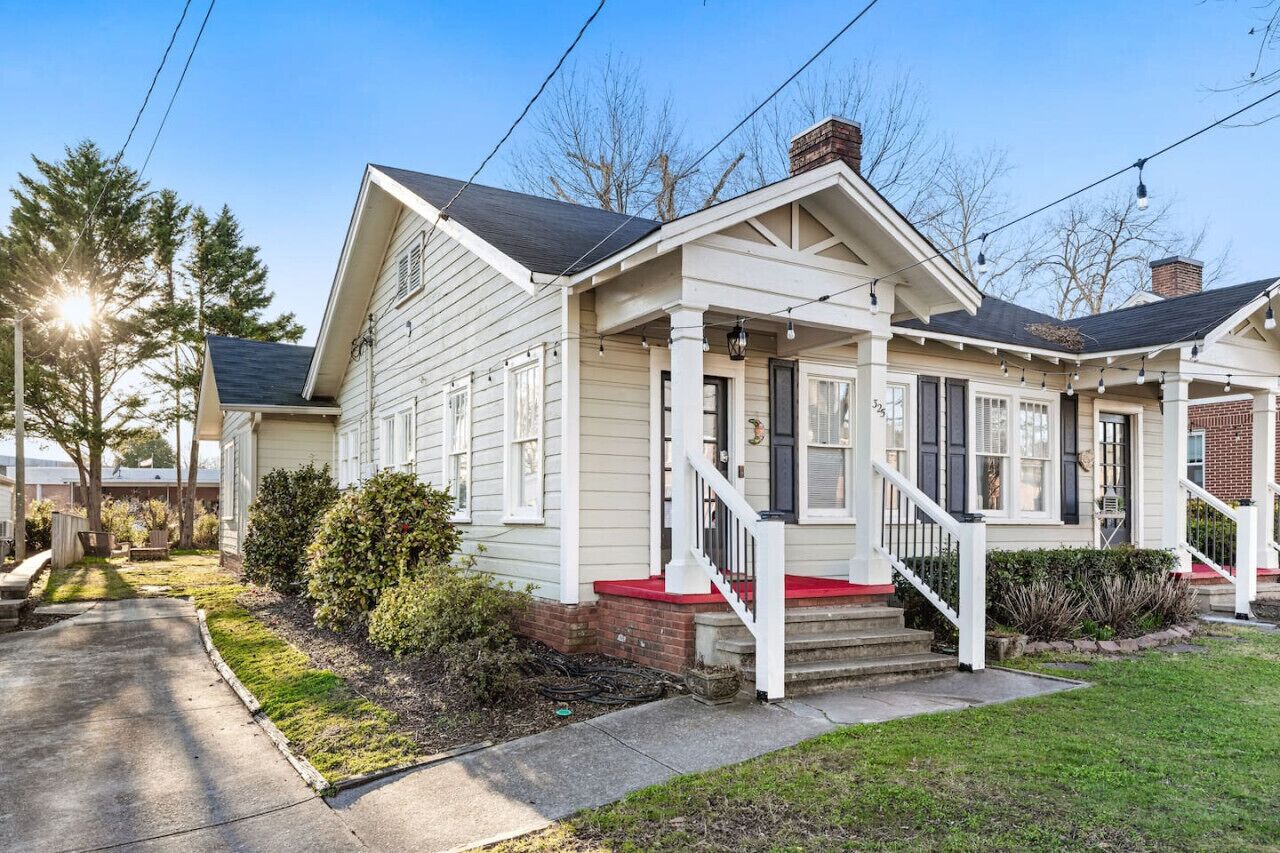 A two-story house with a front porch, a chimney, and a small front yard.