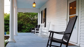 A porch with white columns, a rocking chair, and a bench.