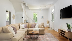 A spacious living room with a beige sectional sofa, a round coffee table, and a patterned rug.