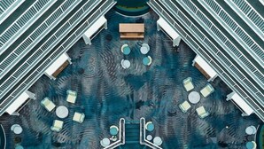 Vue plongeante sur le hall d’un hôtel, avec un espace salon central, plusieurs escaliers et une piscine.