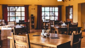L’intérieur d’un restaurant avec des tables et des chaises en bois, de grandes fenêtres et un lustre.