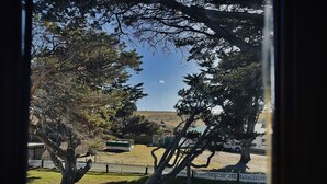 Une vue depuis une fenêtre donnant sur une courClose avec des arbres et un bâtiment situé au loin.