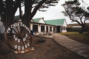 Een landelijk huis met een groot houten wielbord waarop staat: "Casa Grande The Big House".
