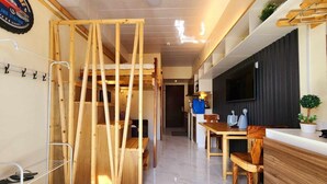 A modern hotel room with a wooden bunk bed, a dining area with a wooden table and chairs, a TV mounted on the wall, and a small potted plant. - Studio - Sleeps 4 - Pets - Smoking - Wifi (Baguio)
