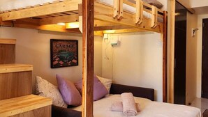 A bunk bed room with a wooden headboard, a bed with a white mattress and pillows, and a framed picture on the wall. - Studio - Sleeps 4 - Pets - Smoking - Wifi (Baguio)