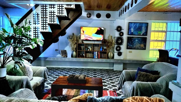 A living room with a staircase, a television, and a bookshelf. - 3 Bed House - Sleeps 20 - Pets - Pool - Garden (La Union)