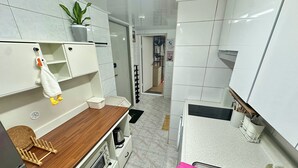 Een compacte keuken met witte kastjes, een houten aanrecht, een spoelbak en een kleine oven.