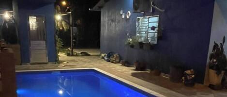 A swimming pool with a blue tint, surrounded by a wooden deck.