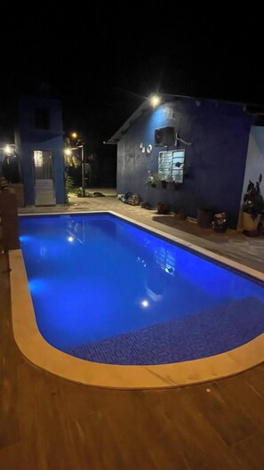 A swimming pool with a blue tint, surrounded by a wooden deck.