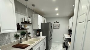 A modern kitchen with white cabinets, a stainless steel dishwasher, and a marble floor.