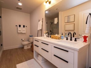 A modern bathroom with a white vanity, black faucets, a large mirror, and a toilet. - Golding Era at 514 Jackson (Oxford)