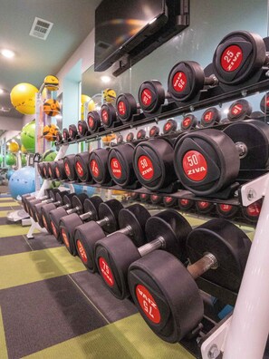 A gym with rows of dumbbells labeled with weights, exercise balls, and a television on the wall. - Golding Era at 514 Jackson (Oxford)