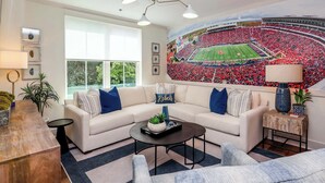 A living room with a large window, a beige sectional sofa, a coffee table, and a wall mural of a football stadium. - Within Punting at 514  by Apex Short Term Stays (Oxford)