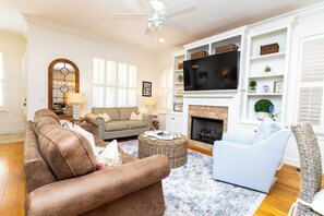 A living room with a sofa, armchair, and a television.