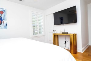 A bedroom with a bed, a television mounted on the wall, a window with blinds, and a small bedside table with a lamp. - Sip Sanctuary by Apex Short Term Stays (Oxford)