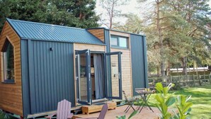 A small, modern cabin with a wooden deck and two Adirondack chairs. - Sugar Hut by Tiny Away (Great Horkesley)