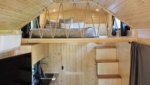 A compact cabin with a loft bedroom, a kitchen area, and a small bathroom. - Sugar Hut by Tiny Away (Great Horkesley)