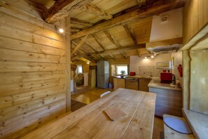 Un intérieur rustique en bois, avec une table à manger, un coin cuisine et une fenêtre bien visible.