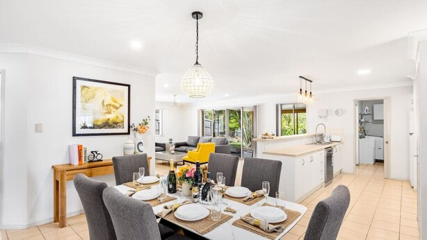 A modern kitchen with a central island, a dining area with a round table, and a living space with a sofa and a yellow chair. - Peaceful 4B2B Sweet Home w/Backyard @ Springfield (Springfield)
