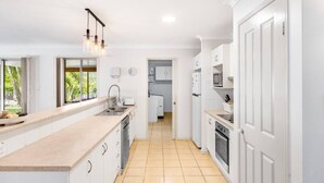 A modern kitchen with white cabinets, a large island, and a view of the garden through the windows. - Peaceful 4B2B Sweet Home w/Backyard @ Springfield (Springfield)