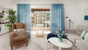 A modern living room with a beige sofa, a white coffee table, and a blue curtain.