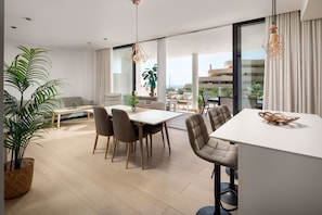Una sala de estar moderna con comedor, ventanas amplias y vistas al exterior.