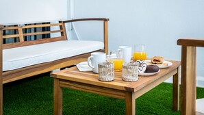 A breakfast setup with a wooden table, white mug, glass of orange juice, and pastries on a green artificial grass floor. - Miraflores Refurbished by Alfresco Stays (Mijas Costa)