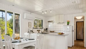 A modern kitchen with white cabinetry, a central island, and a dining area with white chairs. - "Lavrans" - 1km from the sea by Interhome (Ebeltoft)