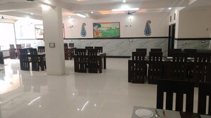A spacious dining area with marble walls and wooden chairs. - Abhinandan Palace (Udaipur)