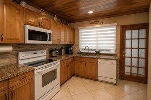 Una cocina con gabinetes de madera, microondas, estufa y lavavajillas.