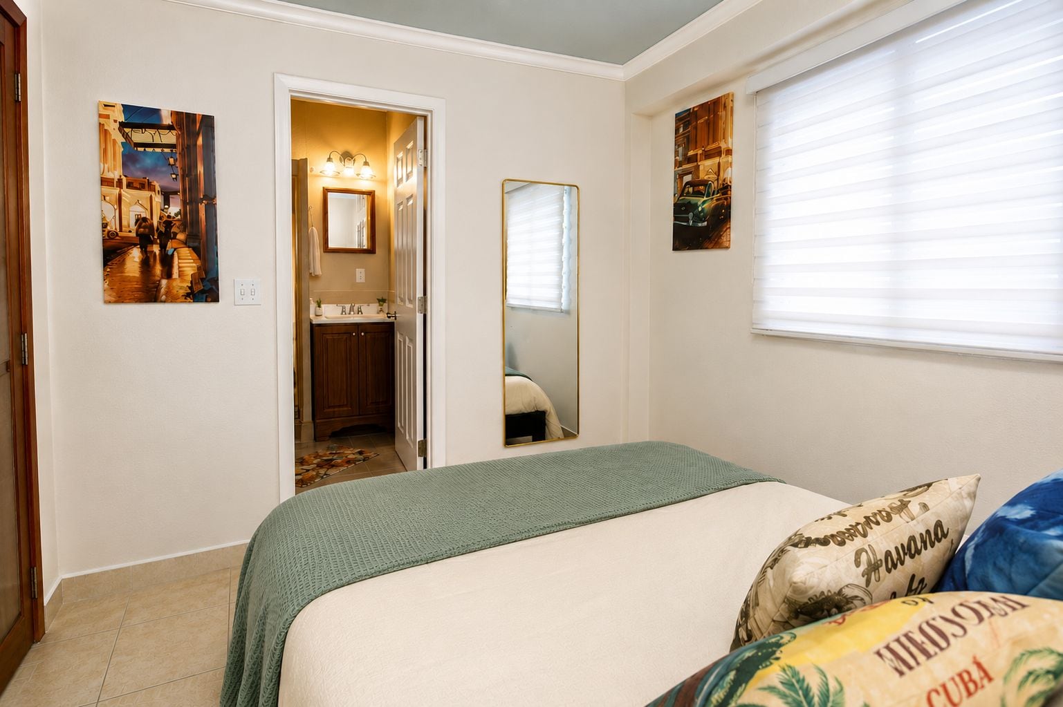 A bedroom with a bed, a mirror, and artwork on the walls.