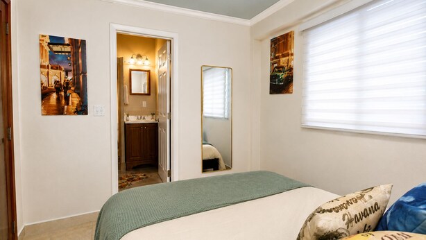 Une chambre à coucher avec un lit, un miroir et des œuvres d’art accrochées aux murs.