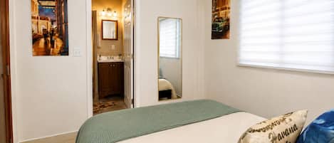 Une chambre à coucher avec un lit, un miroir et des œuvres d’art accrochées aux murs.