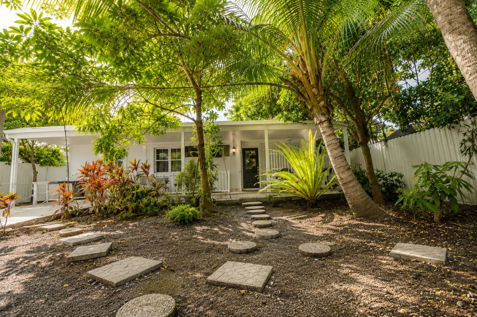 A house with a porch, surrounded by a garden with stepping stones and various plants.