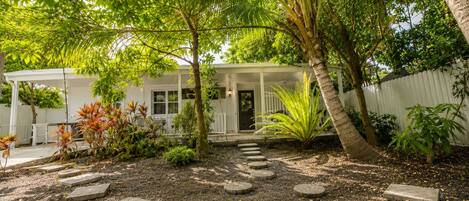 A house with a porch, surrounded by a garden with stepping stones and various plants.