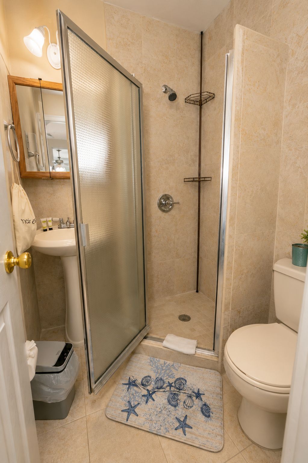 A bathroom with a glass-enclosed shower, a toilet, and a sink.