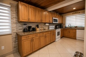 A kitchen with wooden cabinets, a microwave, a stove, and a dishwasher. - House In The Heart of Miami (Miami)