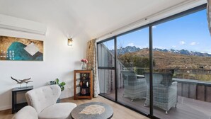A balcony with wicker furniture, a round table, and a view of mountains. - Lakehouse at Panners (Queenstown)