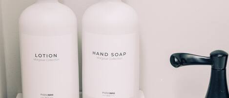 Two white bottles labeled 'LOTION' and 'HAND SOAP' from the Margaux Collection on a white tray.