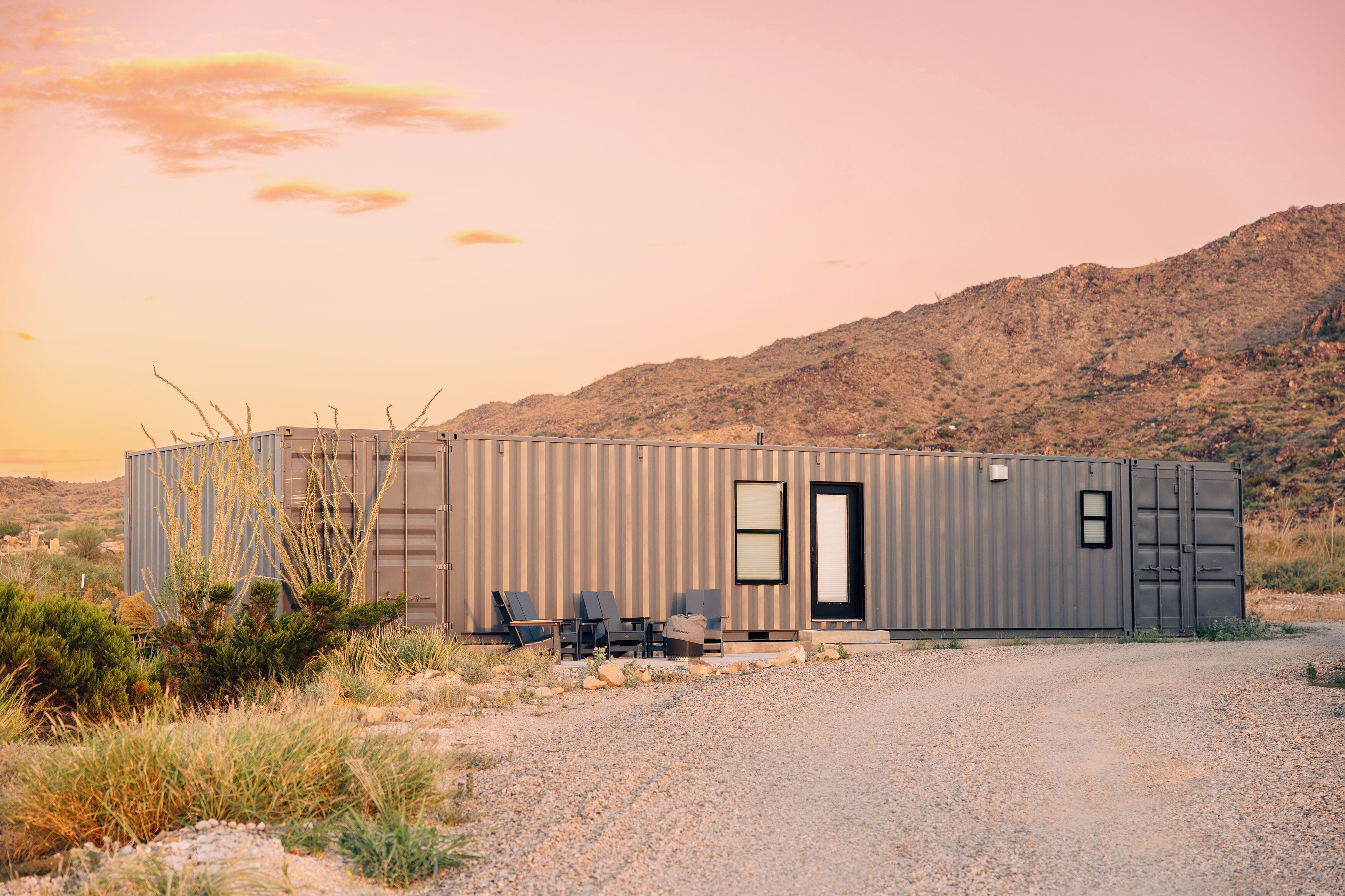 A single-story metal building with a door, windows, and a gravel driveway.